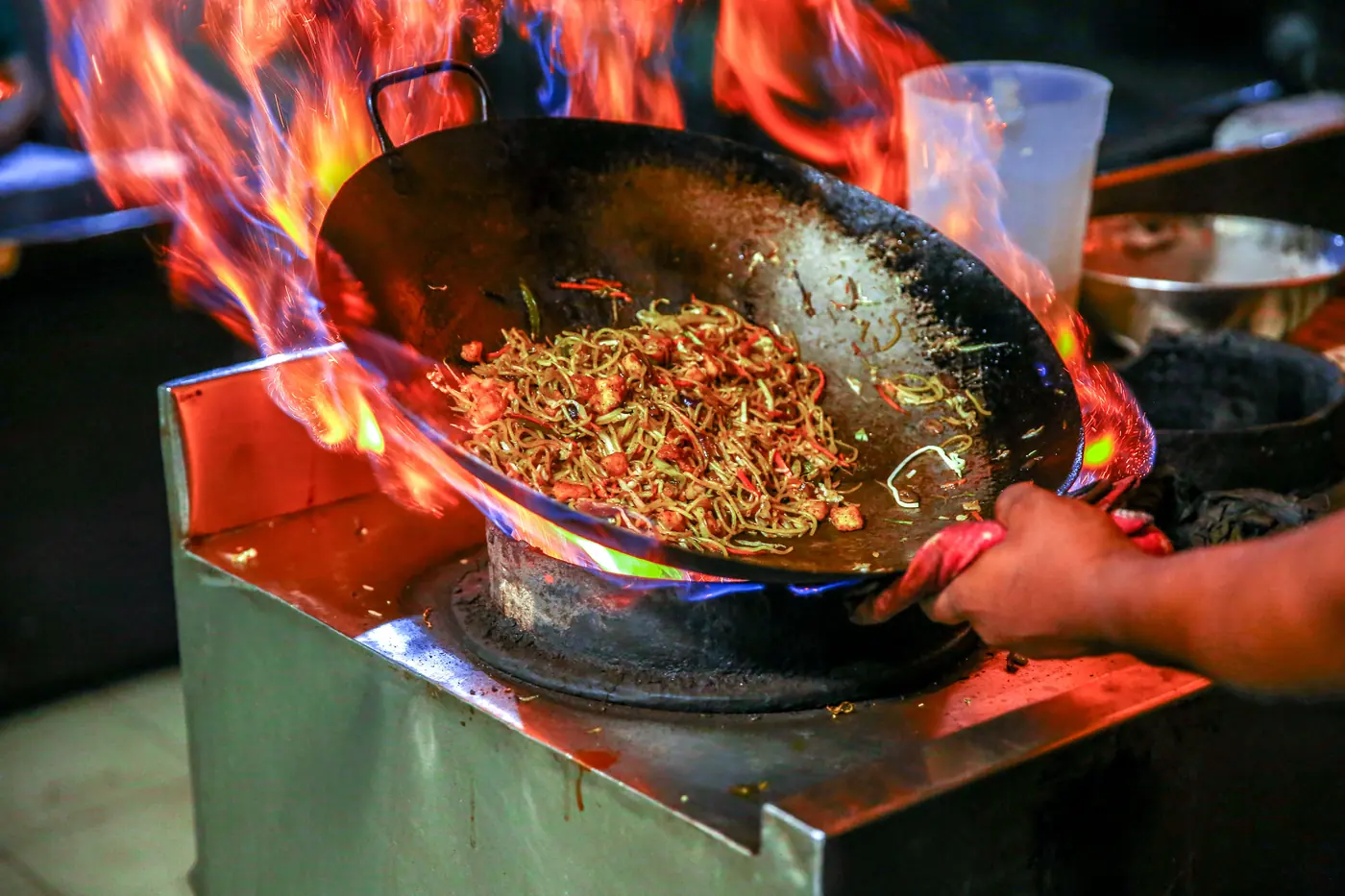 Noodles being tossed in a wok over high heat