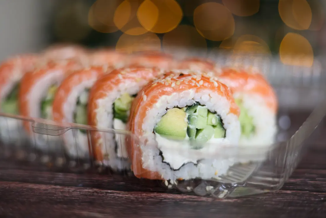 Sushi rolls packed neatly in a clear takeout container
