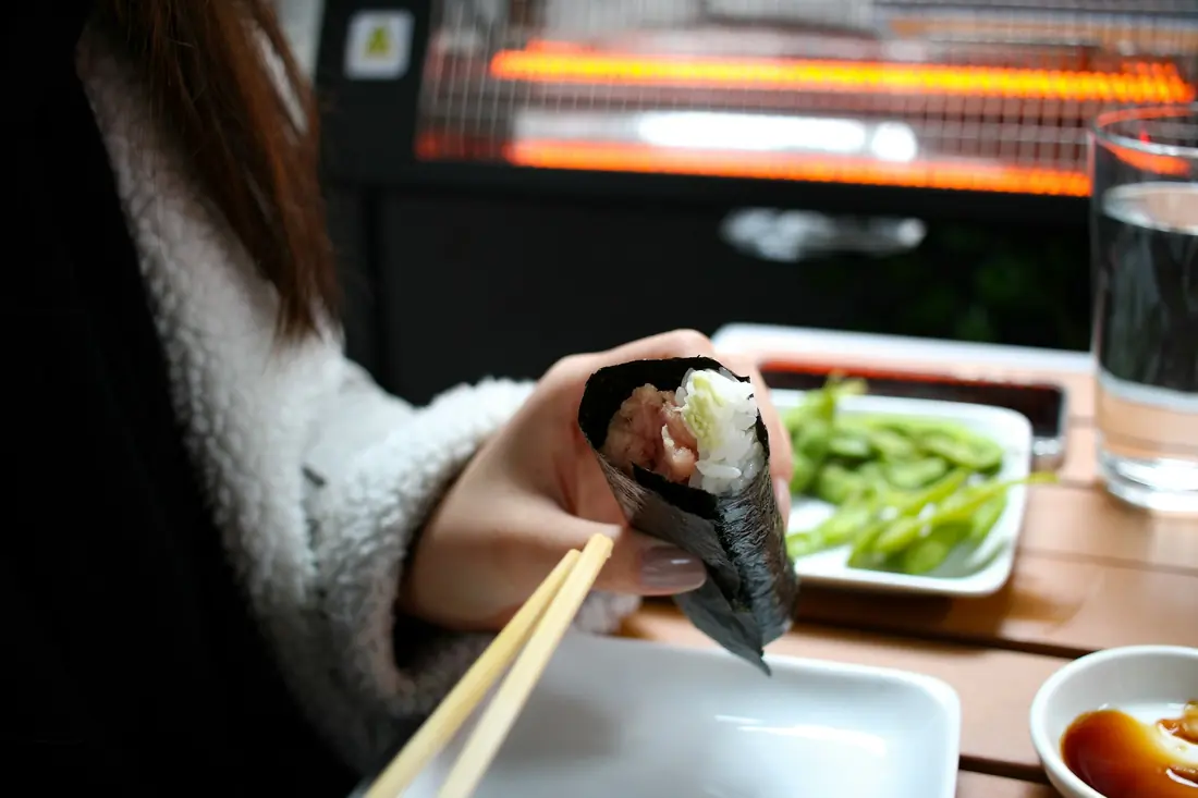 A seaweed cone filled with rice and fish, held in one hand