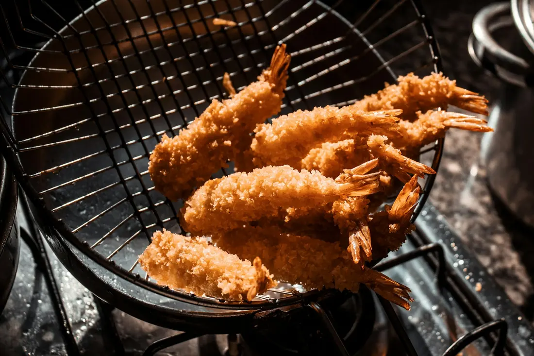 Battered prawns frying to a golden colour in hot oil