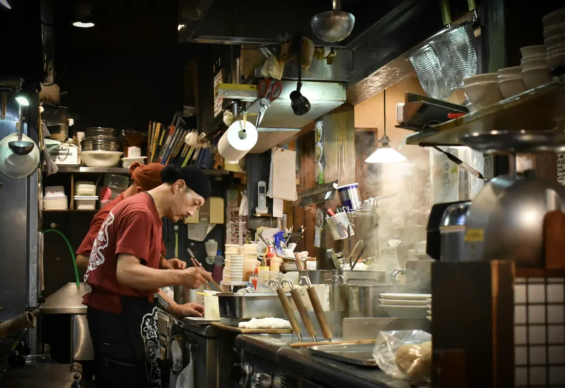 A chef cooking on a griddle in front of seated diners