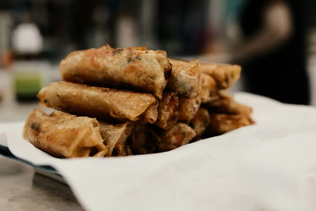 Thin crispy fried rolls stacked on a board