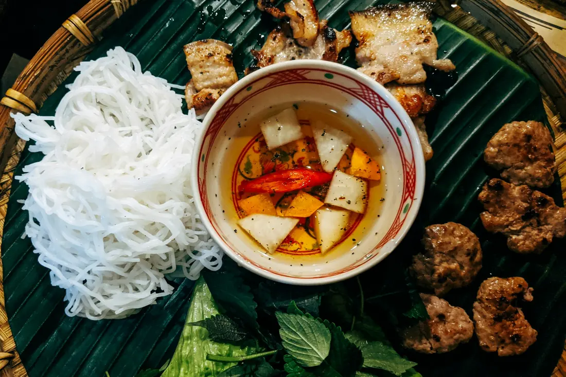 A noodle bowl served with fresh herbs