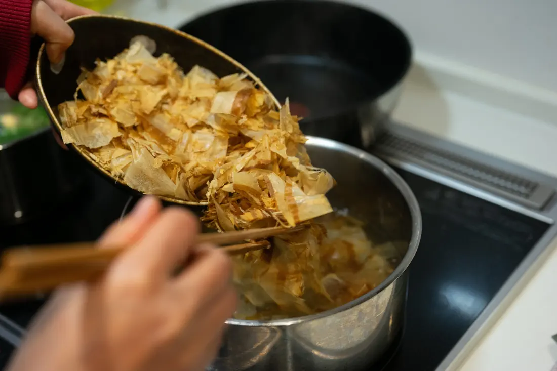 Pale dried flakes being added to a pot